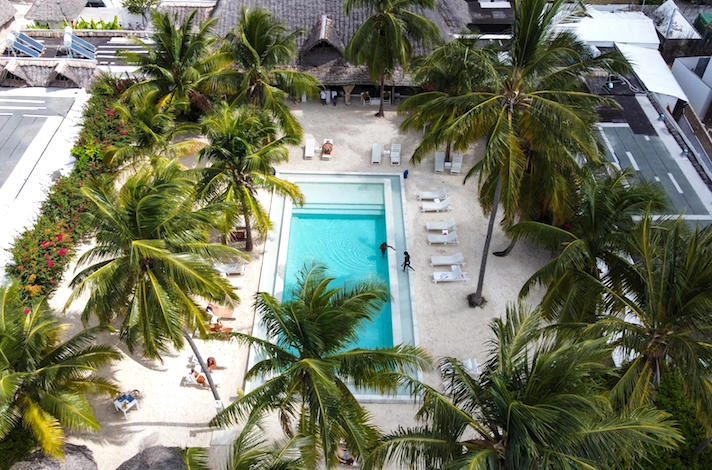 Zanzibar hotel The Loop Beach Resort swimming pool, palm trees and guests sun bathing Our Zanzibar Hotel Group