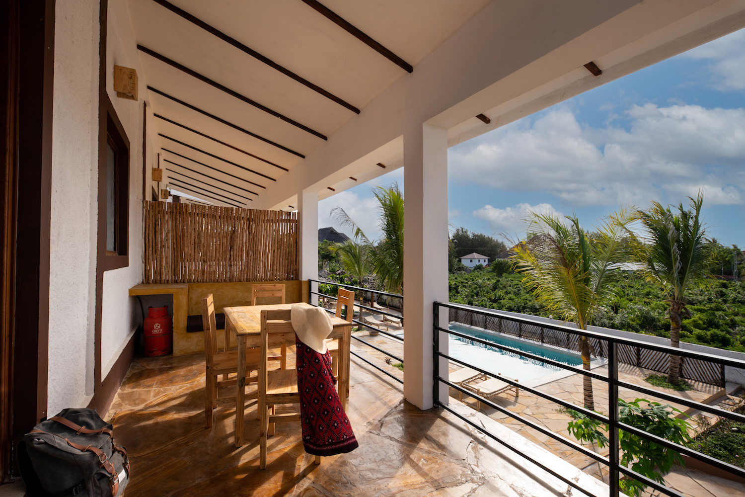 Our Zanzibar Group Nyumbani Residence veranda with chairs and view of pool one bedroom apartment